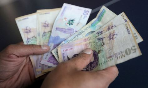 Funcionário conta pesos colombianos em loja de Bogotá