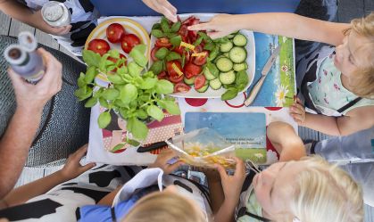 Crianças preparam salada em família/Getty Images