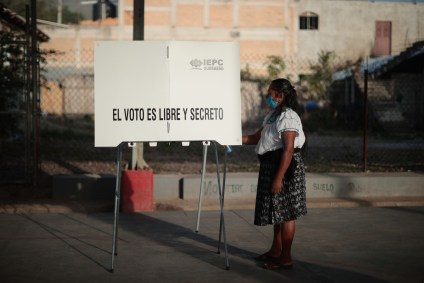 Mesária desinfecta estação de votação em Atzacoaloya, no México