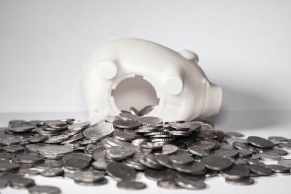 Porco cofrinho aberto com moedas espalhadas ao seu redor