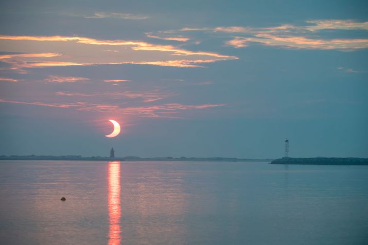 Sol nasce atrás do farol quebra-mar de Delaware, em Lewes / Aubrey Gemignani/NASA via Getty Images