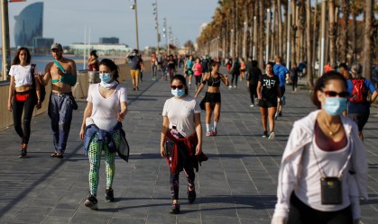 Pessoas caminham na orla de Barcelona.