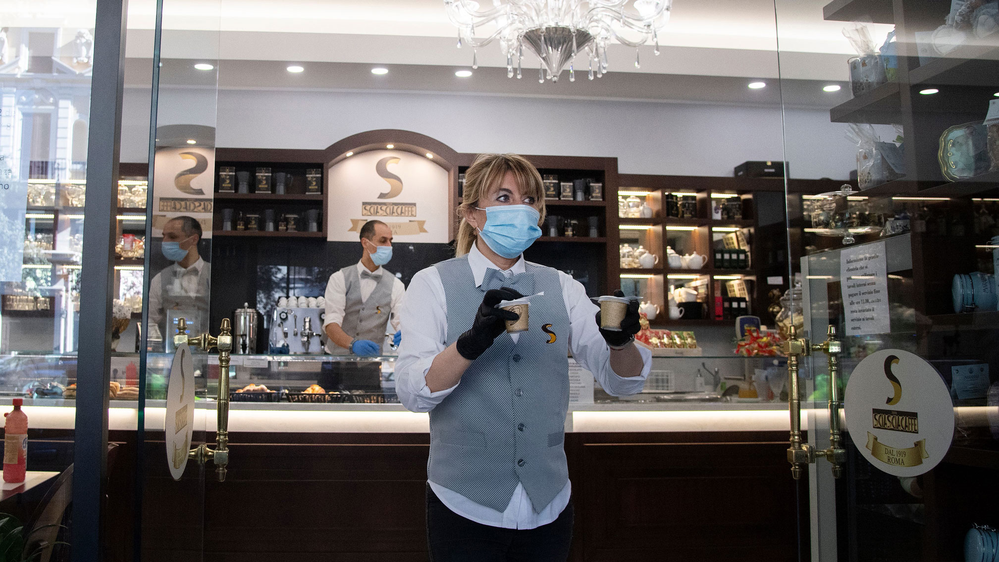 De máscara, garçonete entrega café para viagem em Roma, na Itália