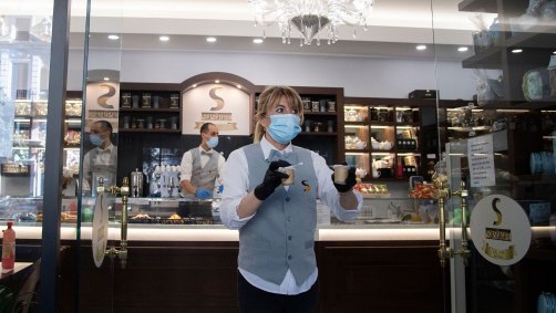 De máscara, garçonete entrega café para viagem em Roma, na Itália