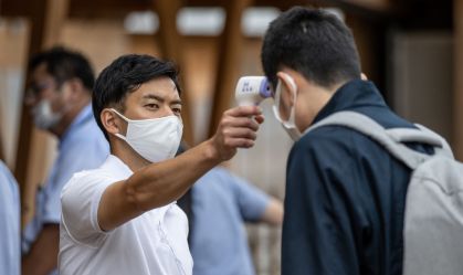 Funcionário checa a temperatura de homem 