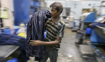 Funcionário descarrega jeans de uma máquina de tingimento na Índia