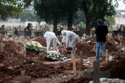 Coveiros enterram caixão em cemitério do RJ usando roupas especiais