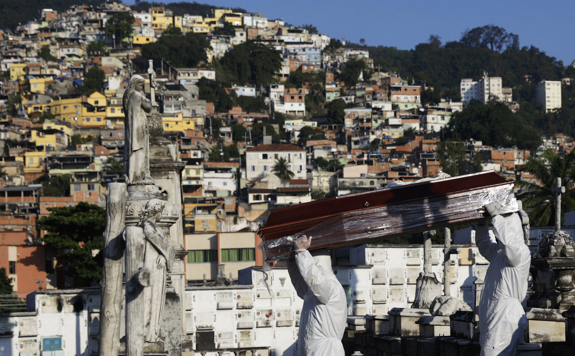 Coveiros com roupas de proteção carregam caixão no Rio de Janeiro