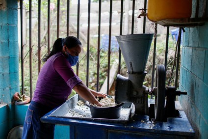Mulher mói milho para fabricar massa de tortilla em El Salvador