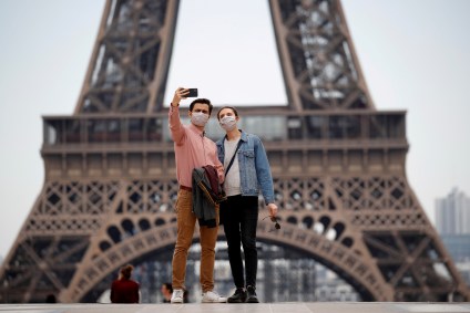 Pessoas usam máscara de proteção perto da Torre Eiffel em Paris