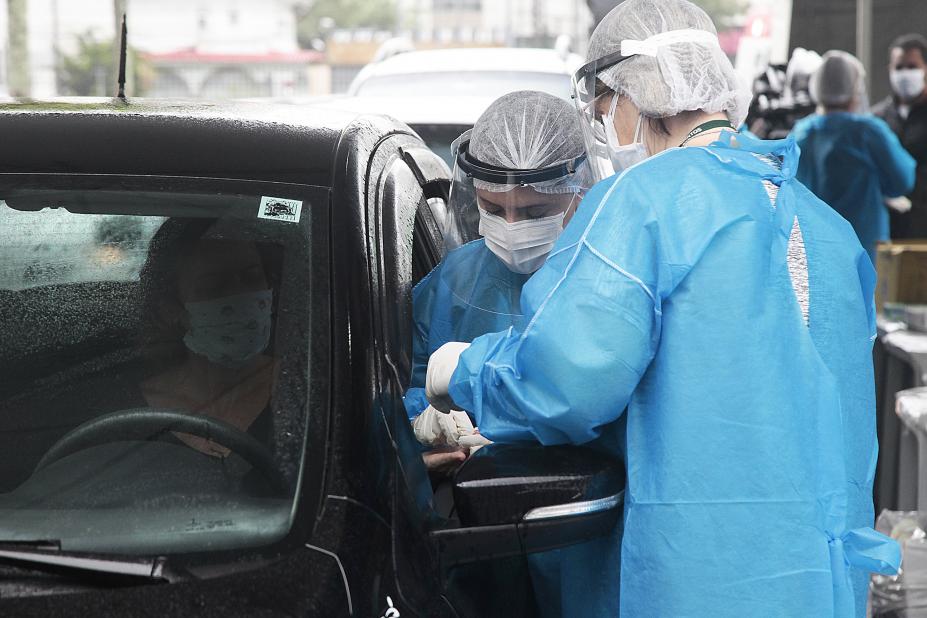 Funcionários fazem testes rápidos de Covid-19 em sistema de drive-thru