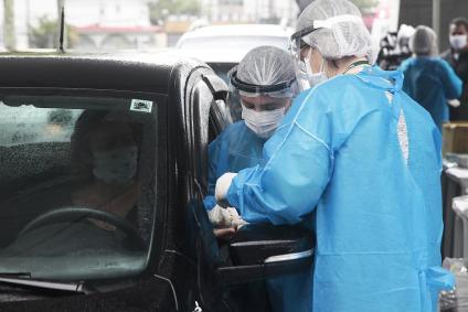 Funcionários fazem testes rápidos de Covid-19 em sistema de drive-thru