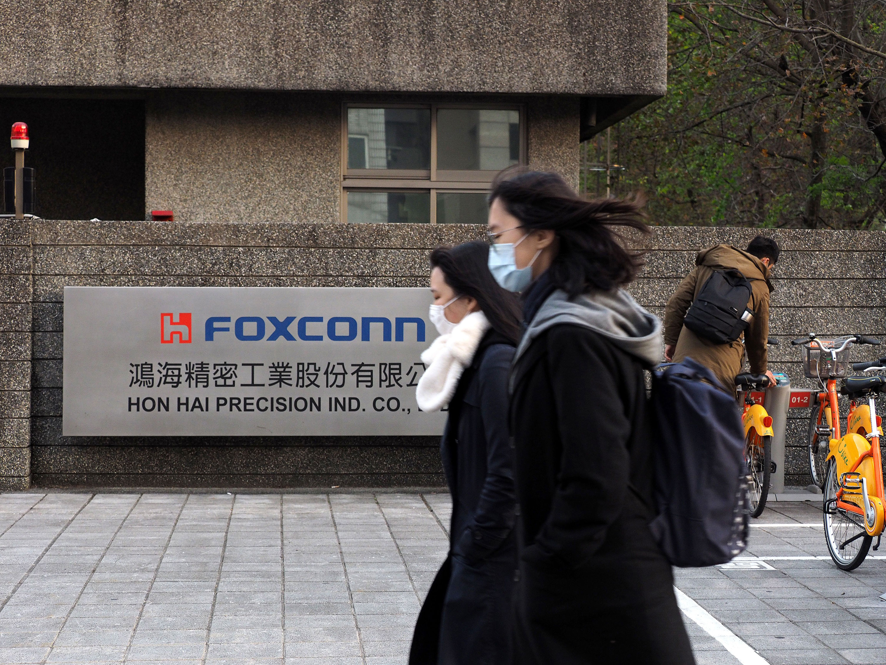 Chineses de máscara caminham na frente da sede da montadora Foxconn
