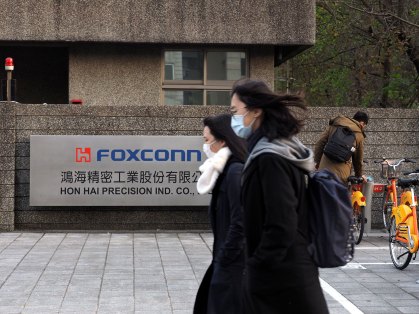 Chineses de máscara caminham na frente da sede da montadora Foxconn