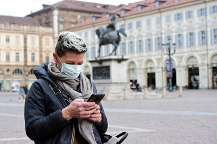 Mulher com máscara de proteção usa celular em Turim, no norte de Itália