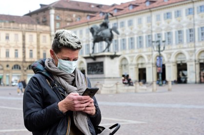 Mulher com máscara de proteção usa celular em Turim, no norte de Itália