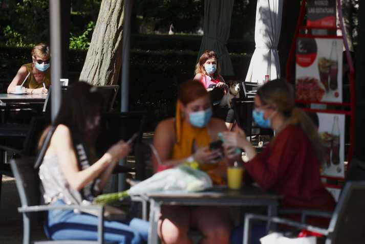 Pessoas com máscara de proteção sentam em mesas de quiosque no Parque del Retiro, em Madrid / Foto: Sergio Perez - 25.mai.2020/Reuters