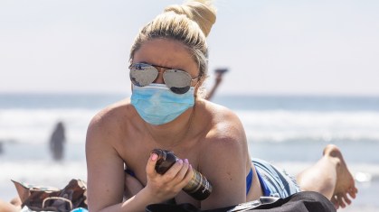 Mulher com máscara na praia durante pandemia da Covid-19.
