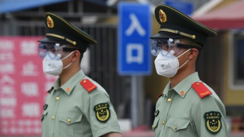 Policiais paramilitares usam máscaras e óculos de proteção, em Pequim, China.