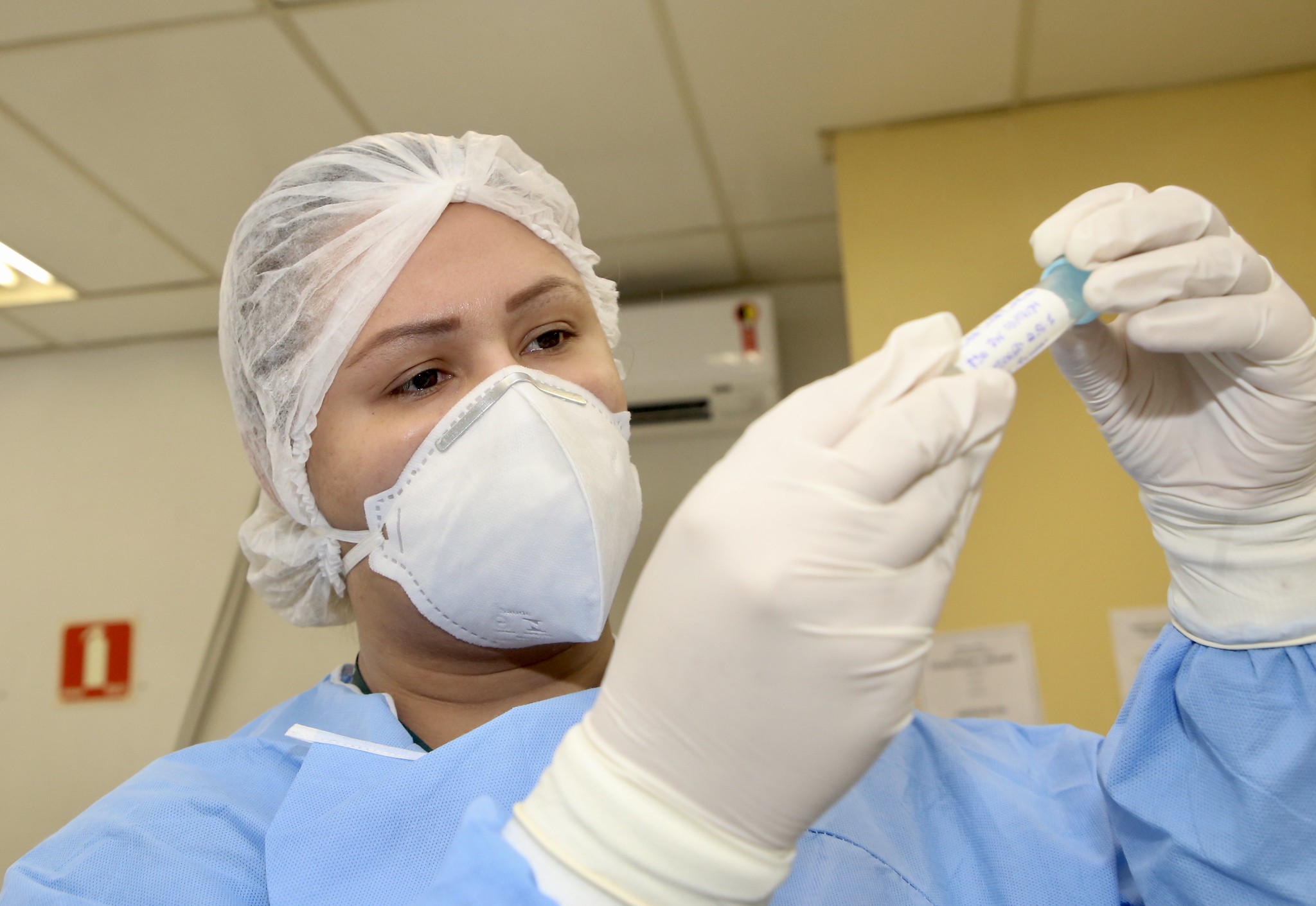 Profissional analisa amostra para teste de detecção de Covid-19