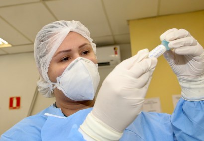 Profissional analisa amostra para teste de detecção de Covid-19