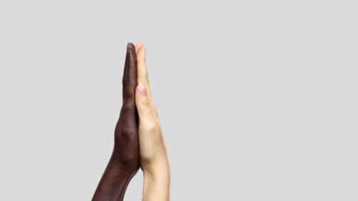 Mãos de pele branca e negra juntas.