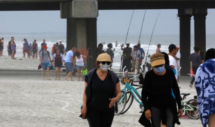 Pessoas caminham em praia na cidade de Jacksonville, na Flórida