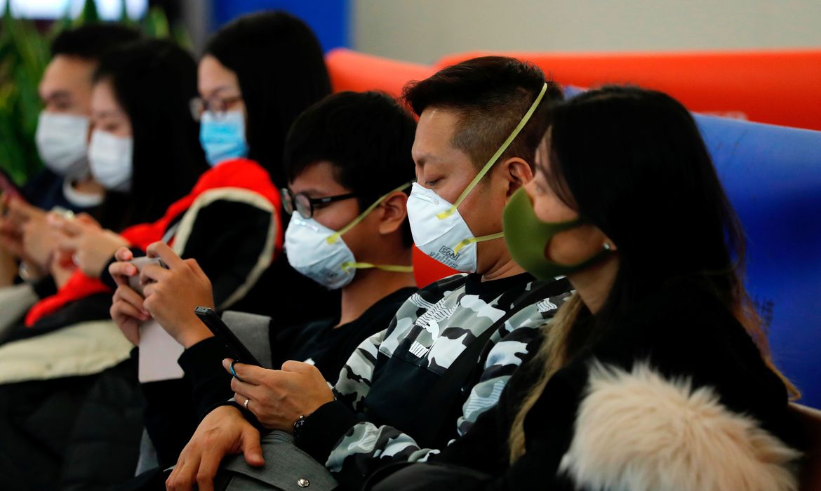 Chineses usando máscara e mexendo no celular