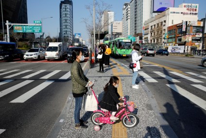 Mãe e filha usam máscaras enquanto caminham por avenida no centro de Seul