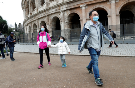 Turistas usam máscaras para evitar coronavírus na frente do Coliseu, em Roma