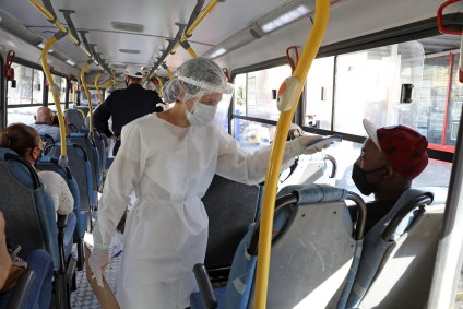 Profissional de saúde afere temperatura de passageiro em ônibus em BH