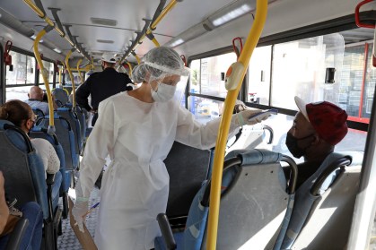 Profissional de saúde afere temperatura de passageiro em ônibus em BH