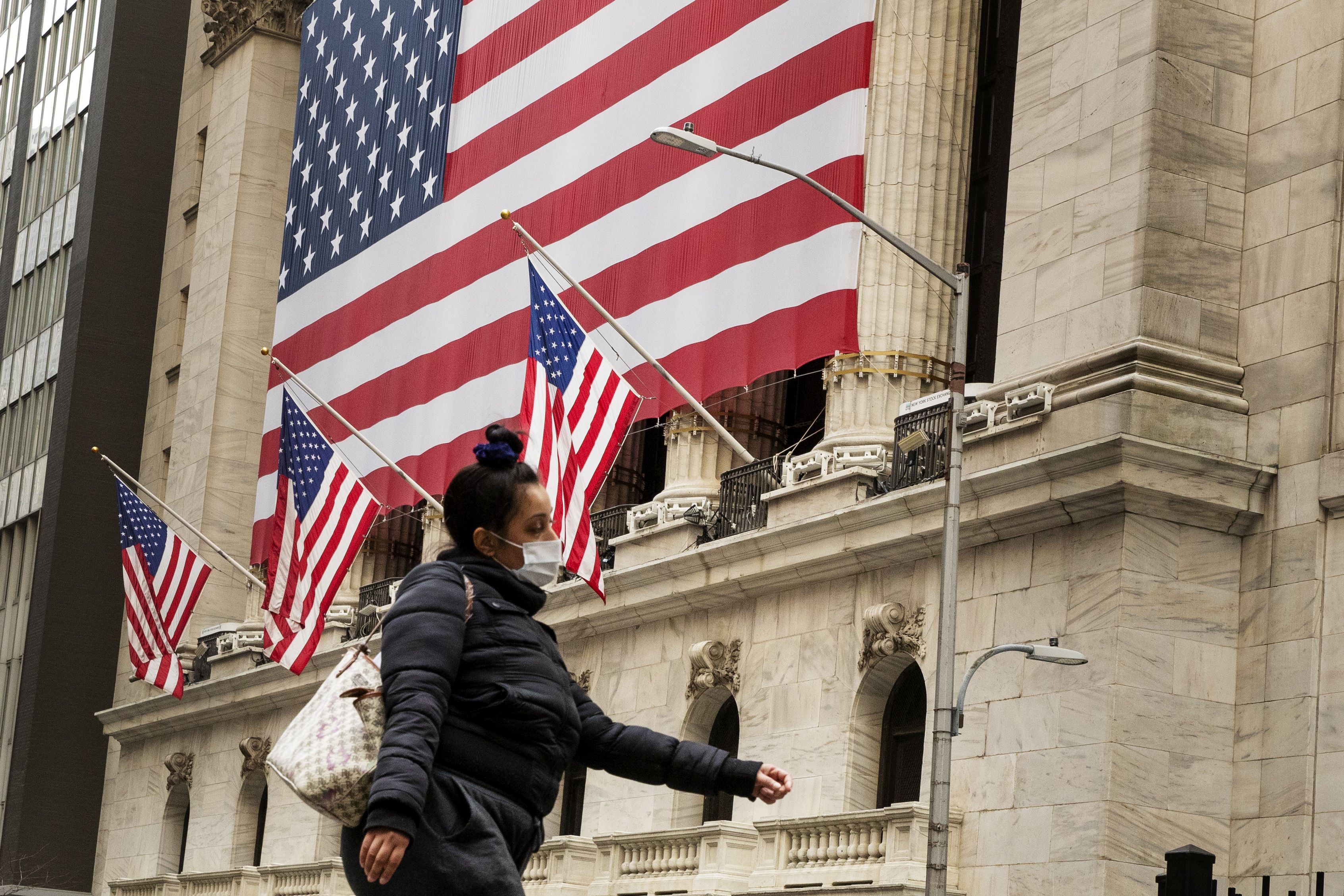 Pedestre caminha de máscara em frente à Bolsa de Valores de Nova York