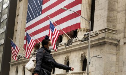 Pedestre caminha de máscara em frente à Bolsa de Valores de Nova York