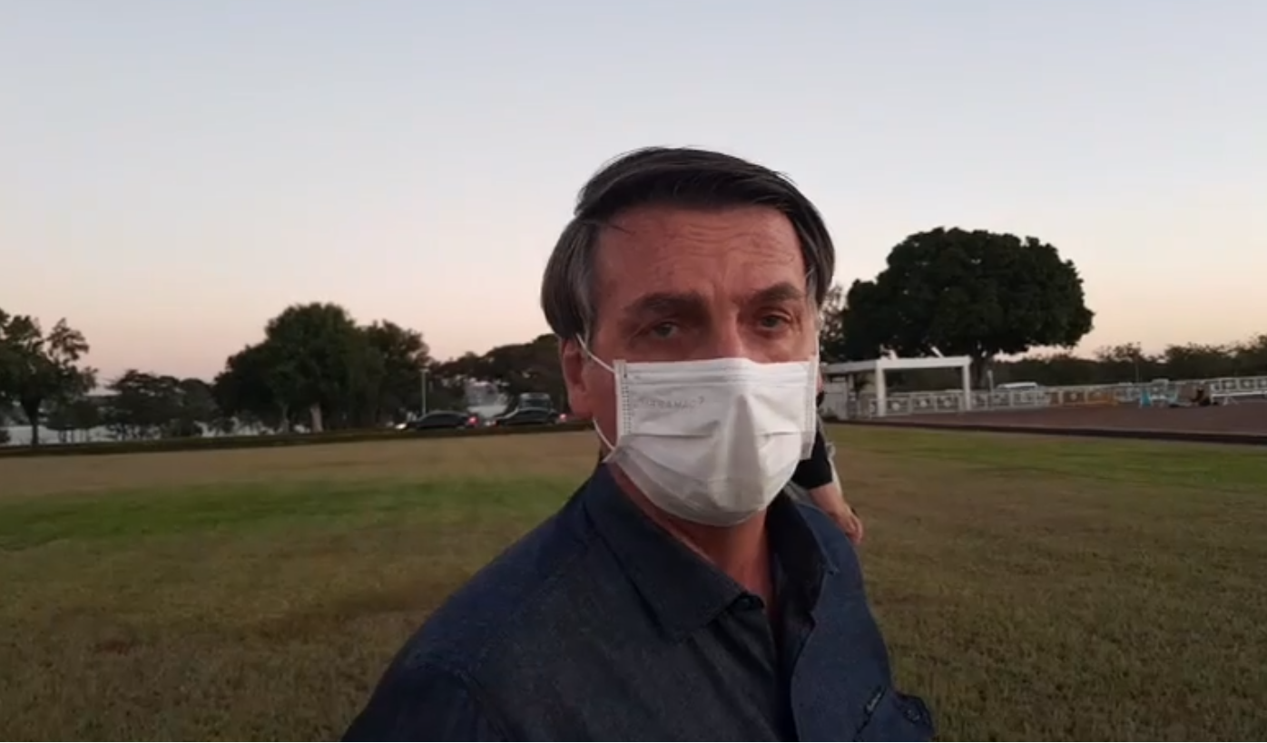 O presidente Jair Bolsonaro usa máscara durante arriamento da bandeira nacional