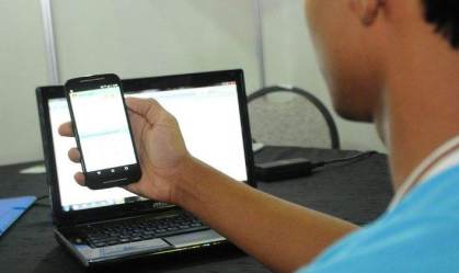 Jovem acessa sistema pelo celular em pelo computador