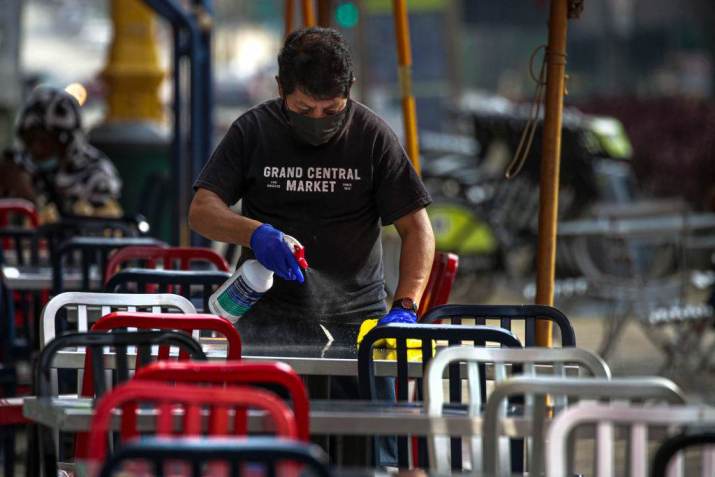 Funcionário higieniza mesas para reabertura de restaurantes em Los Angeles, em 30/03/2021 / Los Angeles Times via Getty Image