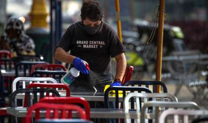 Funcionário higieniza mesas para reabertura de restaurantes