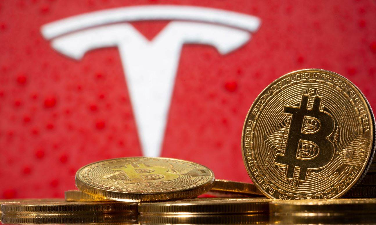 Representação da moeda virtual bitcoin, com logotipo da Tesla ao fundo Representação da moeda virtual bitcoin, com logotipo da Tesla ao fundo