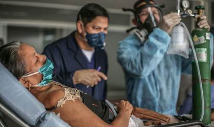 Um médico observa enquanto uma enfermeira verifica o fluxo de oxigênio de uma mu