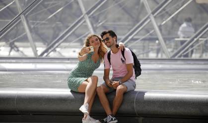 Turistas tiram foto em frente à pirâmide do Louvre