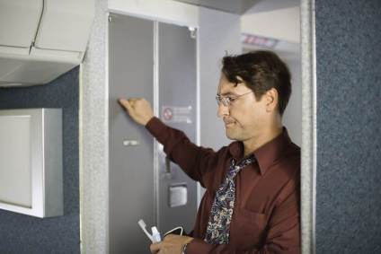 Passageiro na fila para usar banheiro de um avião