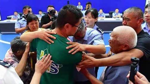 Guo Xinzhen (centro) abraça sua família em reunião em Liaocheng, China, dia 11 d