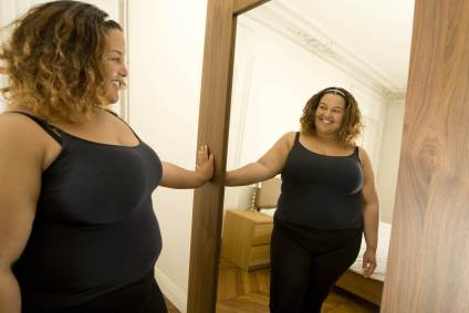 Mulher se olha no espelho/Getty Images