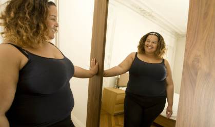 Mulher se olha no espelho/Getty Images