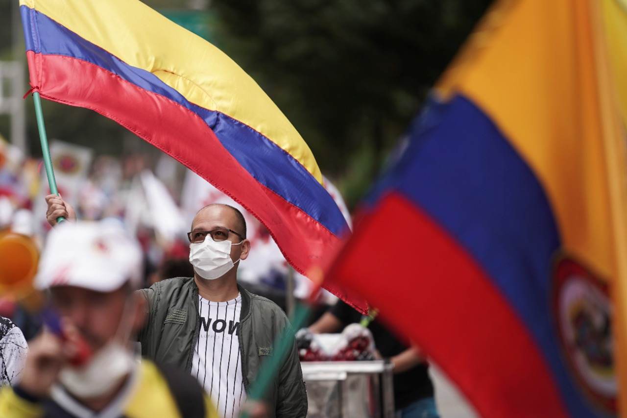 Manifestante acena com bandeira colombiana durante um protesto 