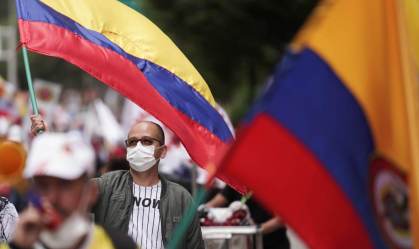 Manifestante acena com bandeira colombiana durante um protesto 
