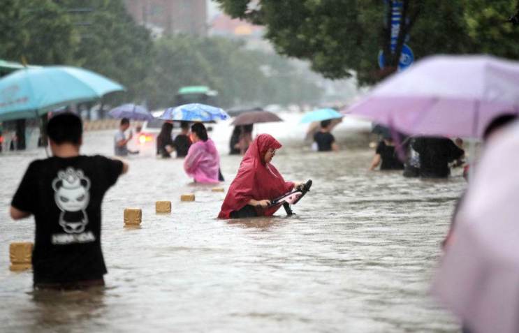 China: pessoas caminham com água na altura da cintura nas ruas de Zhengzhou, na China central / Barcroft Media via Getty Images