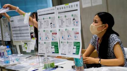 Funcionária entrega teste de Covid-19 no centro de imprensa dos Jogos Olímpicos