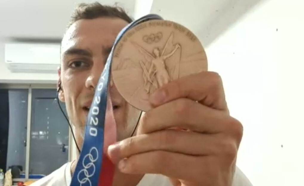 Nadador Fernando Scheffer mostra medalha de bronze durante entrevista à CNN